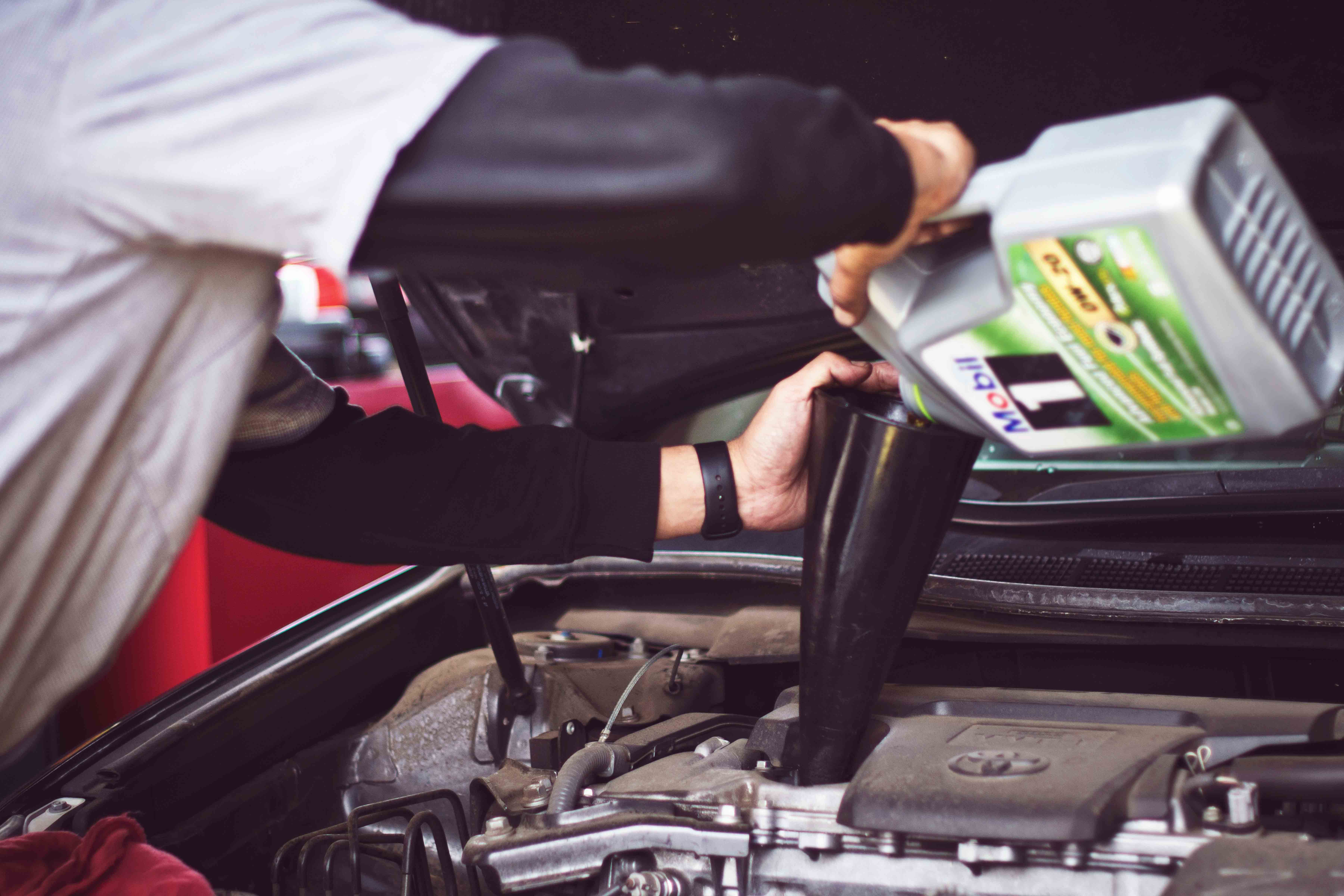 Man pouring oil into engine of car 