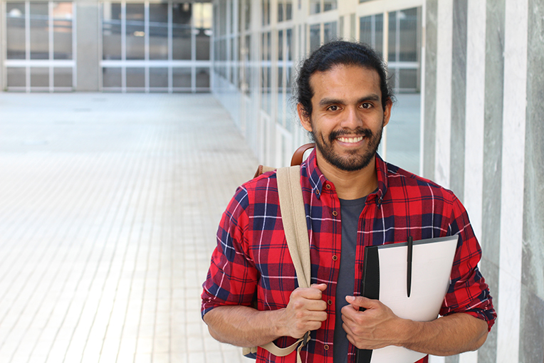 ESL student wearing backpack and holding notebook