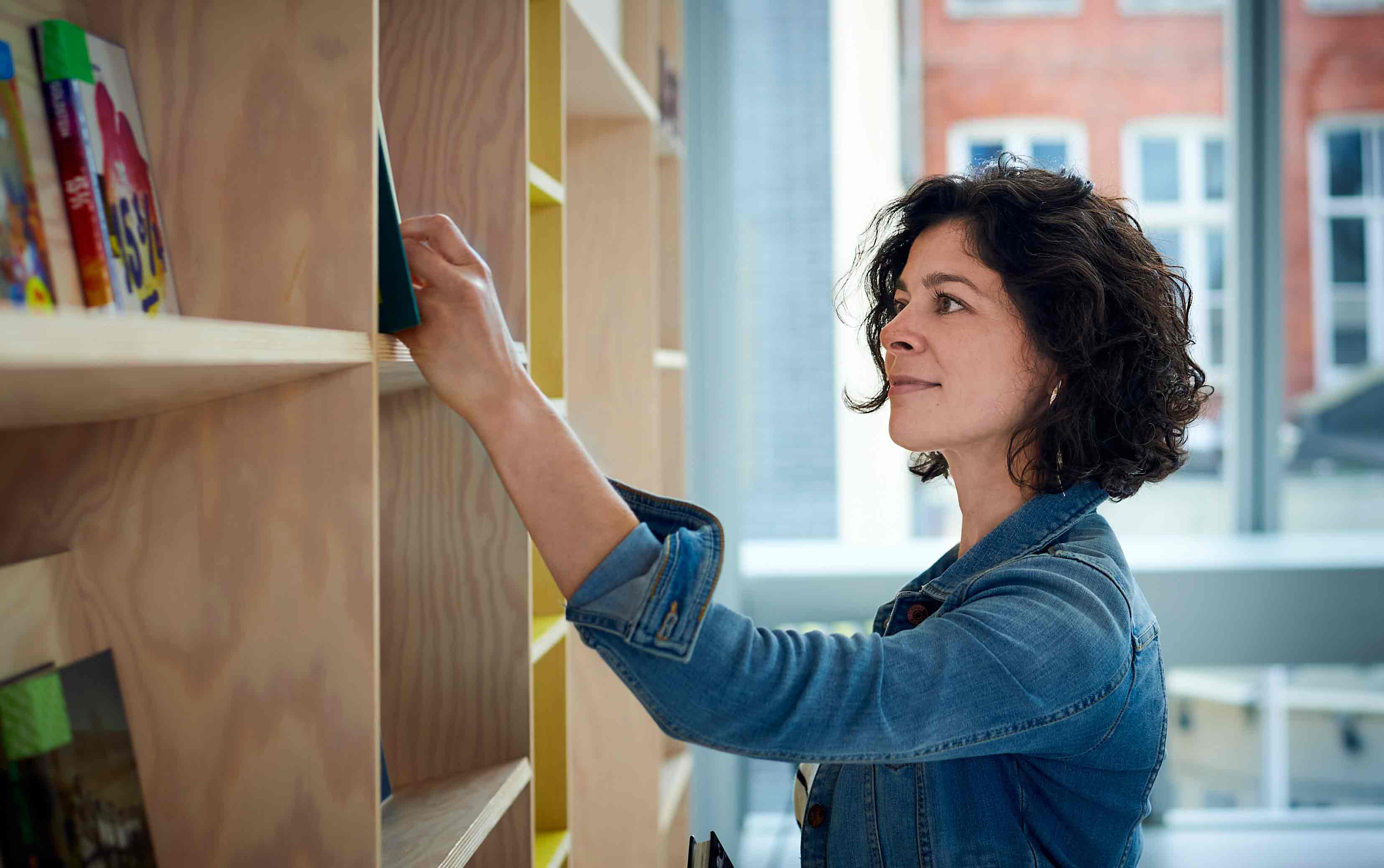 Student reaching for book in library