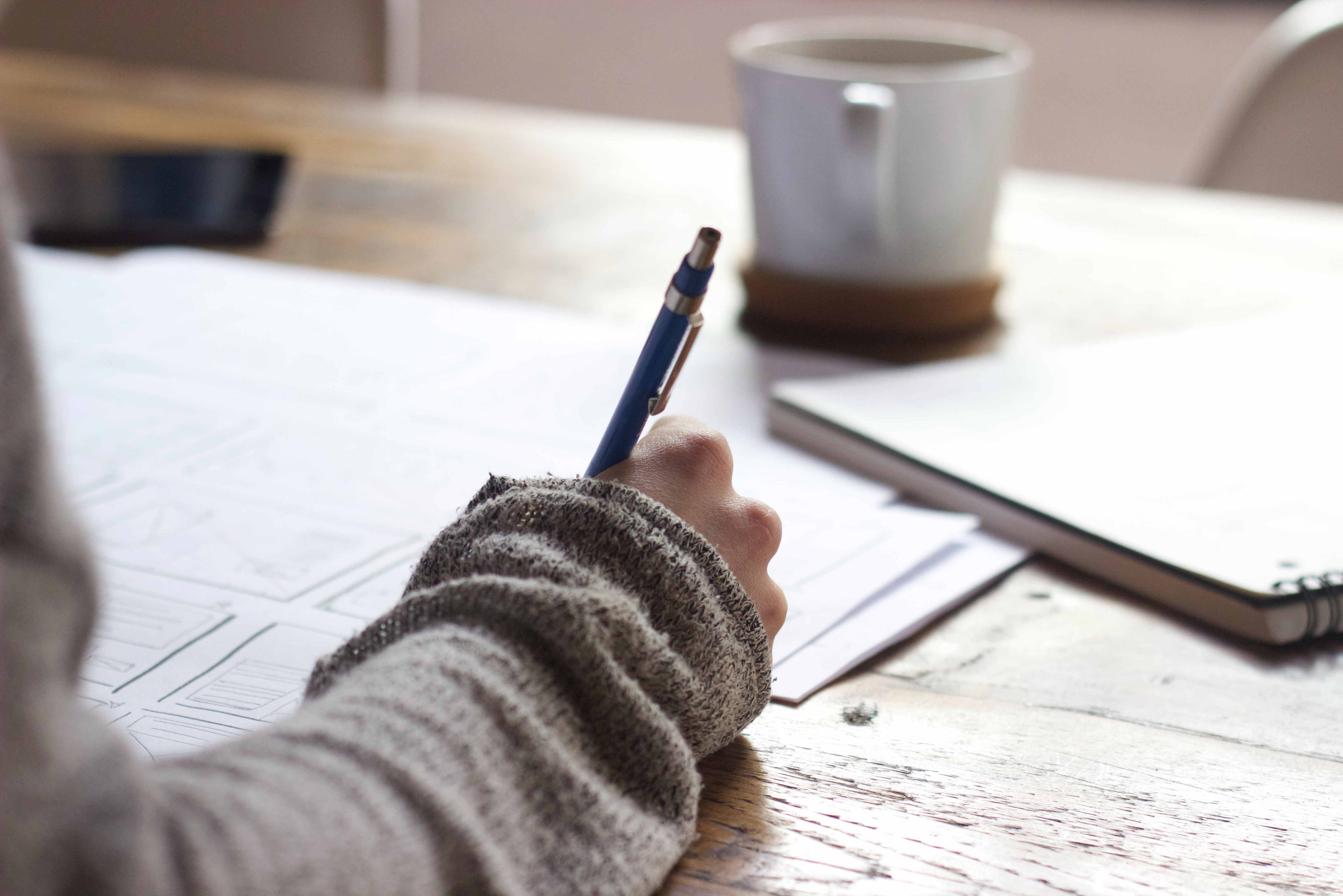 Hand holding pen writing in notebook