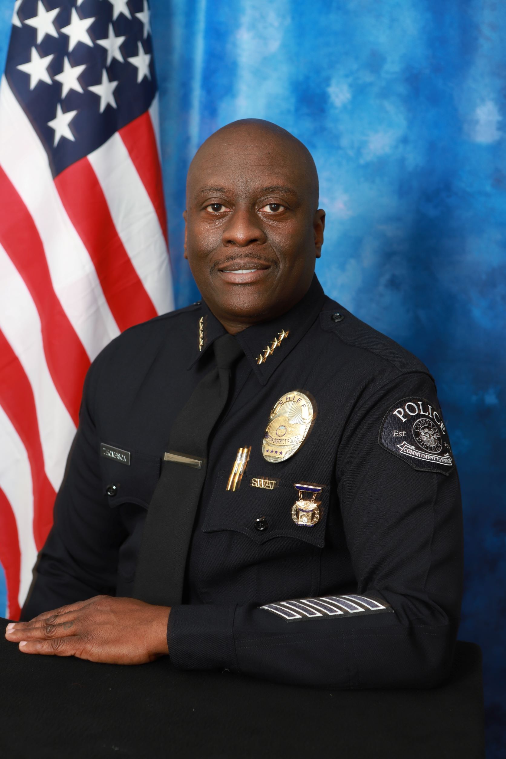 Portrait of Chief Thompson, blue background, American flag on the right