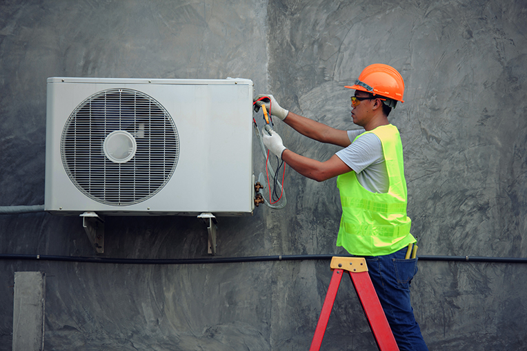 View Program Air Conditioning & Refrigeration Man in hard hat fixing air conditioner 
